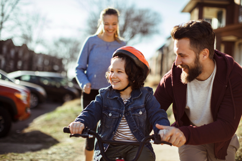 Happy family teaching their child to ride a bike on a sunny day in Kirkwood, MO